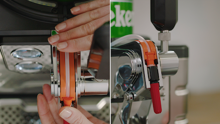 Hands attaching a tap handle to a beer dispenser.