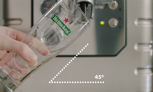 Hand holding a Heineken glass at a 45-degree angle under a beer tap.