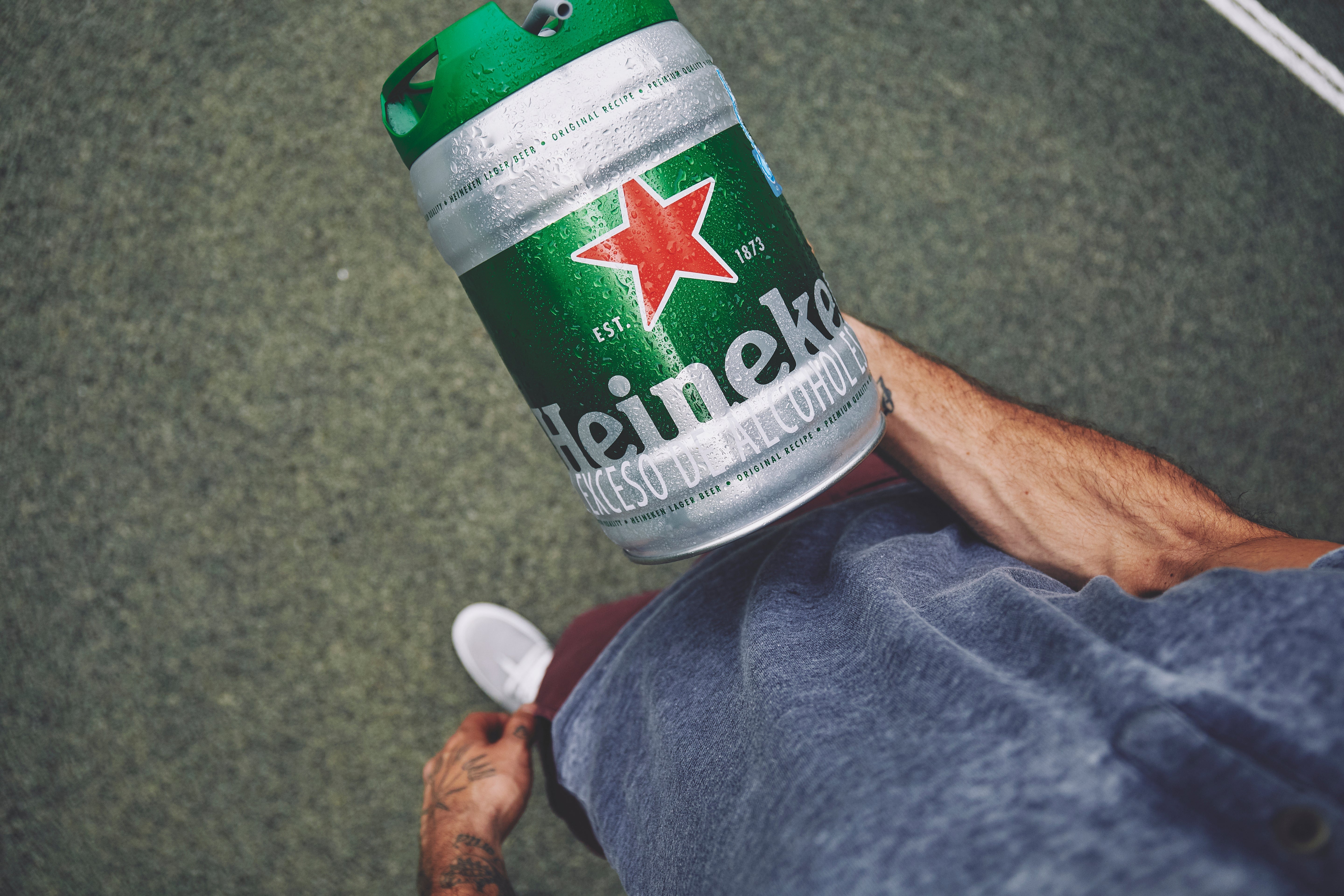 Person holding a Heineken beer keg on a concrete surface