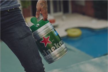 Man holding a Heineken 5L keg next to a pool