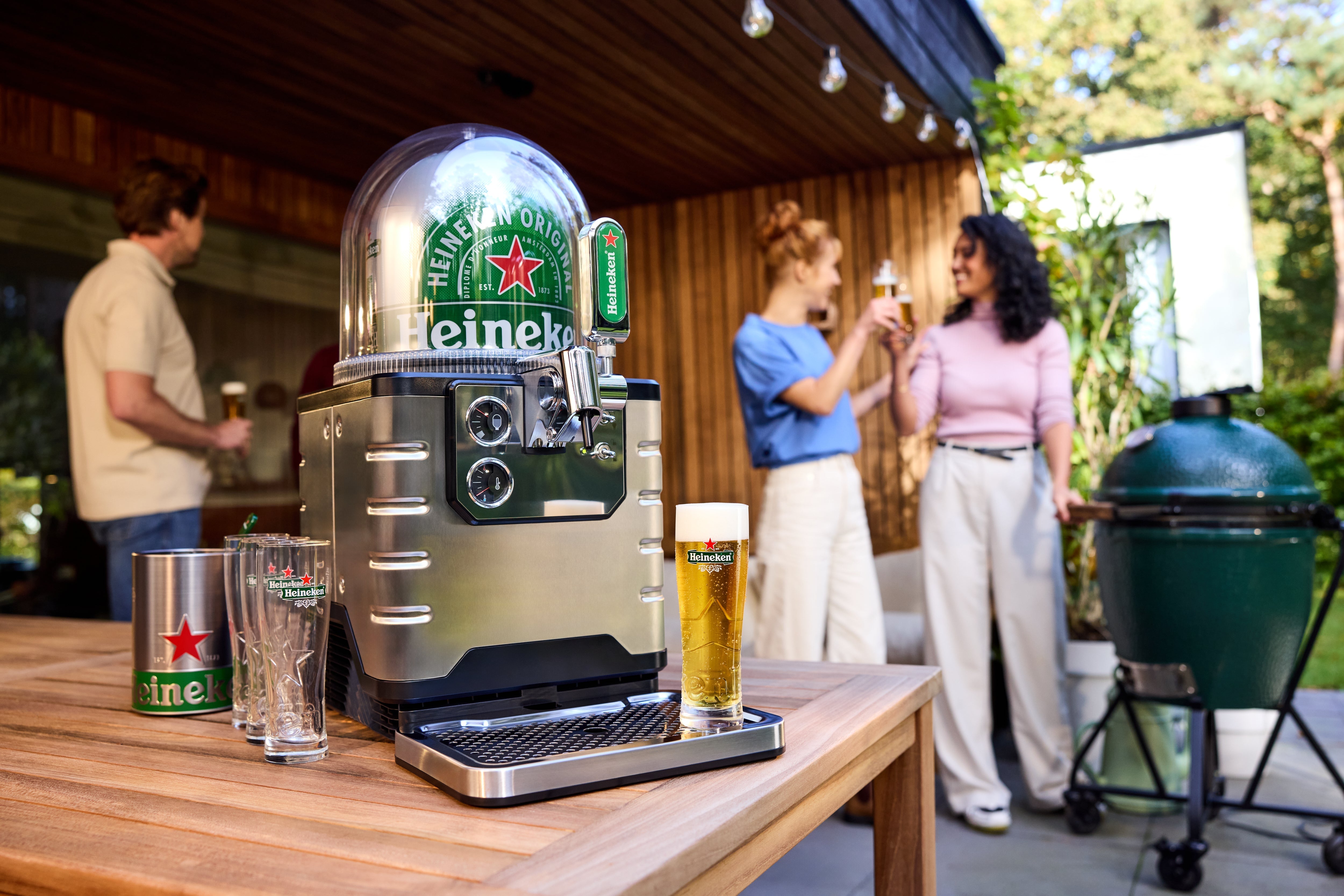 BLADE beer machine on an outdoor wooden counter with a glass of beer and people in the background.