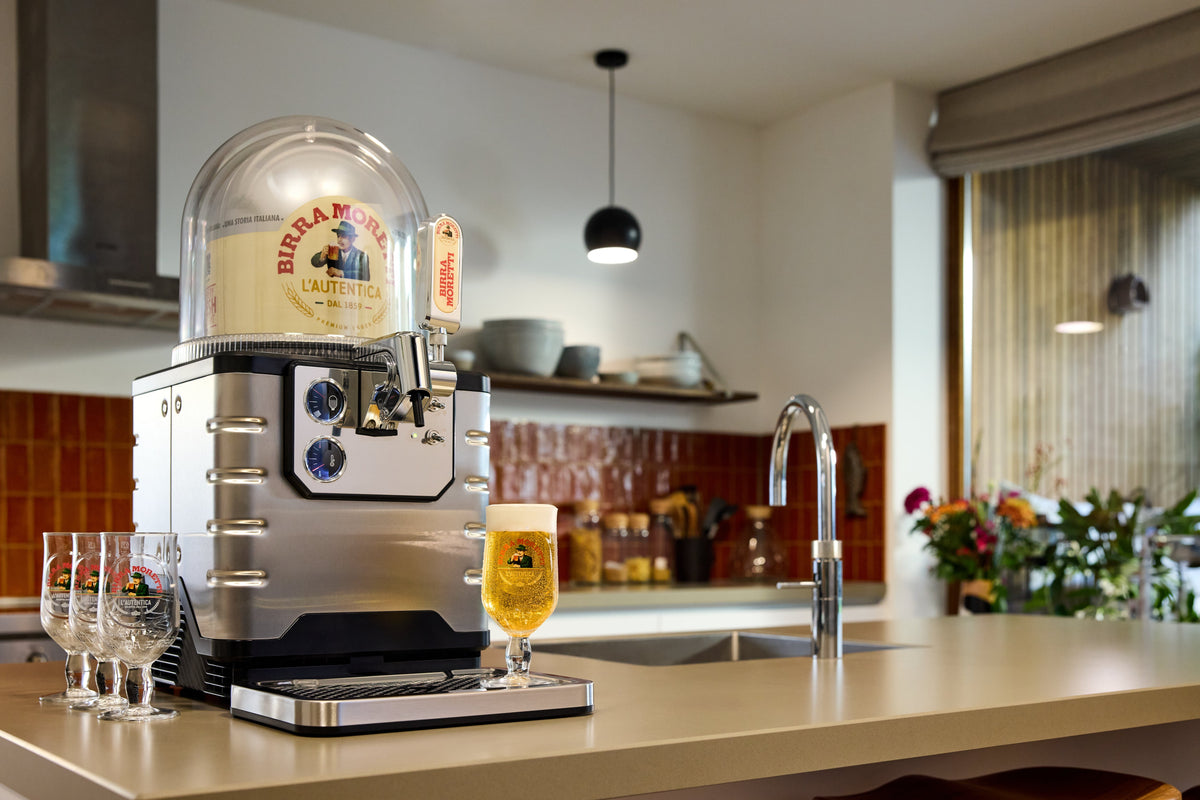 BLADE una macchina per la birra sul piano della cucina con un bicchiere di birra e altri bicchieri.