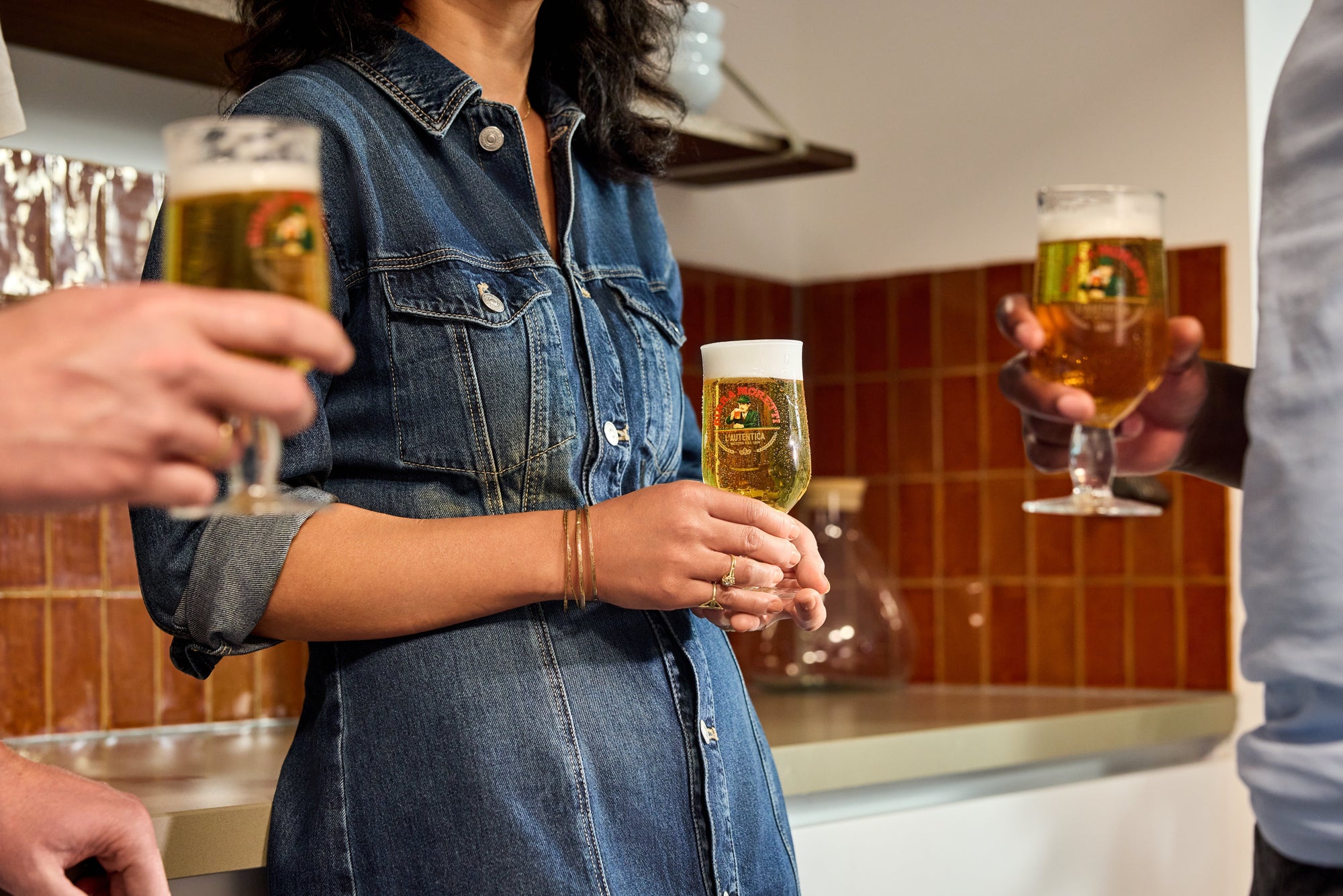 Persone con un bicchiere di birra in mano in una cucina