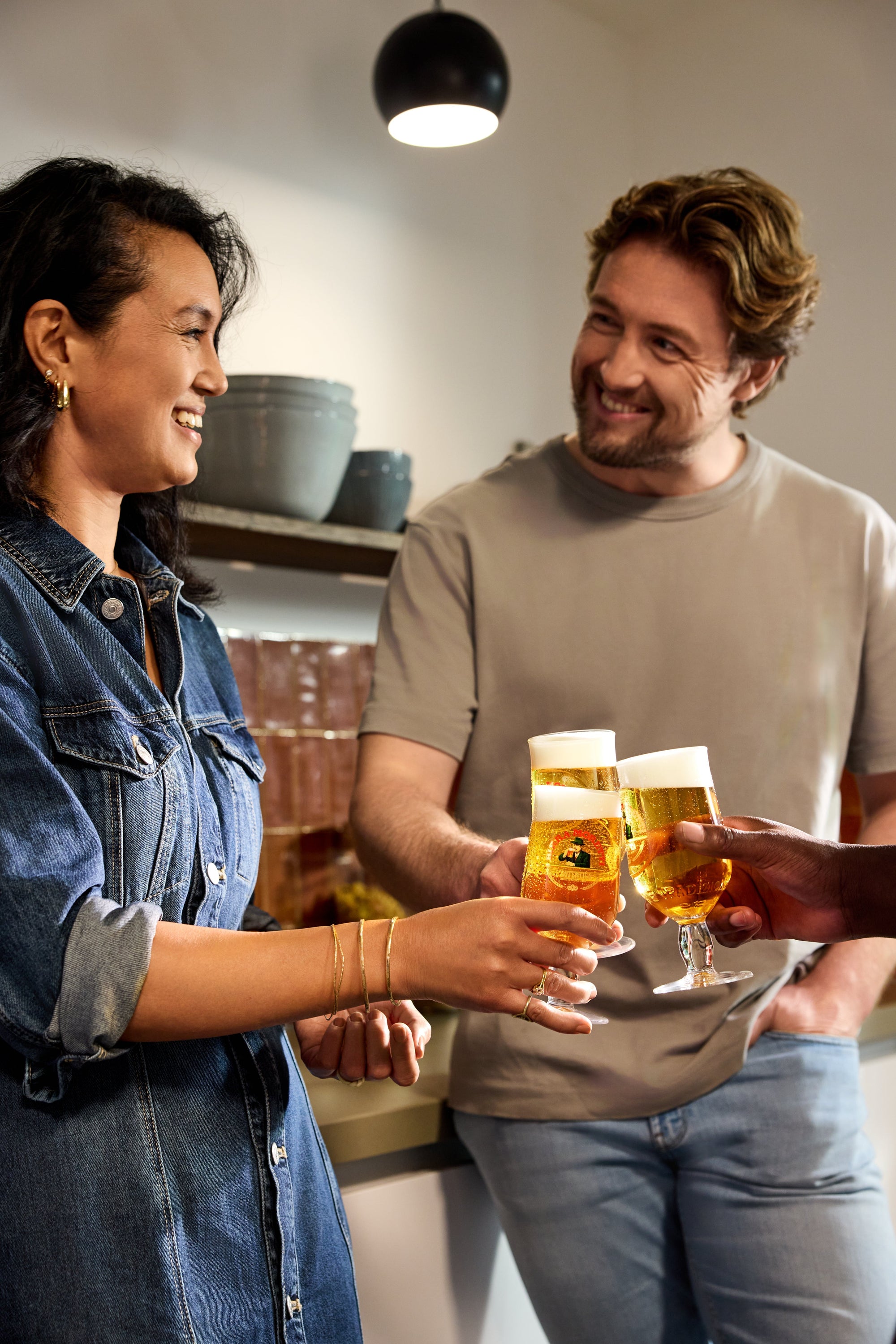 Two people in a kitchen holding glasses of beer