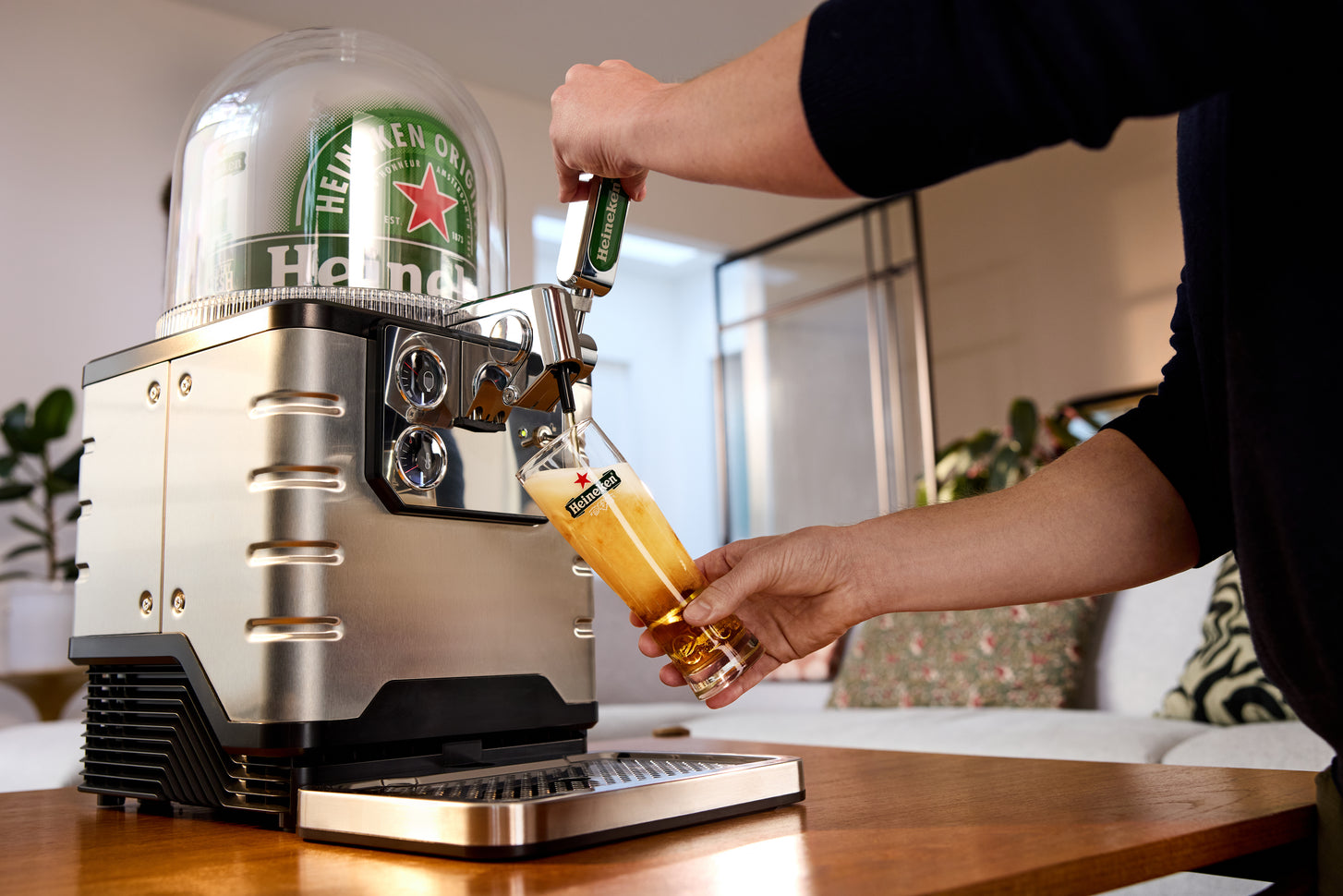 Una persona che versa la birra da una spina in un bicchiere, con una spina Heineken.