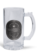Een heldere glazen bierpul met een zilverkleurig metalen Heineken plaatje aan de voorkant.
