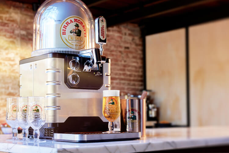 A BLADE beer machine with a Birra Moretti Tap Handle, a Birra Moretti beer keg, a fresh glass of Birra Moretti on the drip tray and three empty Birra Moretti glasses.