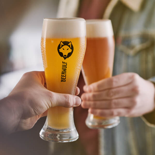 Two people cheers with fresh glasses of beer served in Beerwulf beer glasses.