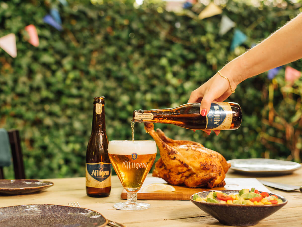 Een bord met gegrild vlees en bijgerechten naast een glas bier, perfect voor een zomerse BBQ.