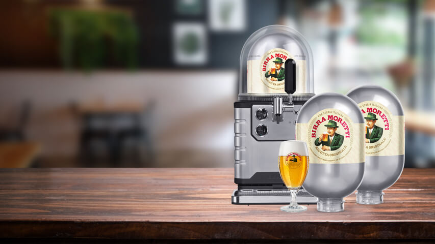 A BLADE beer machine on a table with a Birra Moretti keg inside, two Birra Moretti kegs next to it and a glass of Birra Moretti in front.