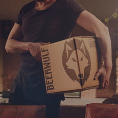 A person carrying a Beerwulf box under their arm in a home setting.