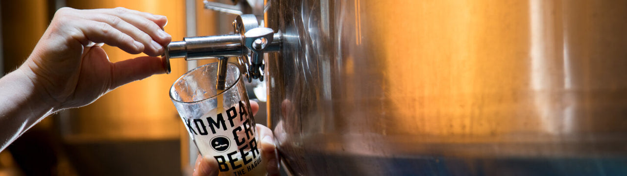 A hand using a beer tap to pour beer in a glass