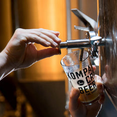 A hand turning a tap to pour beer in a glass