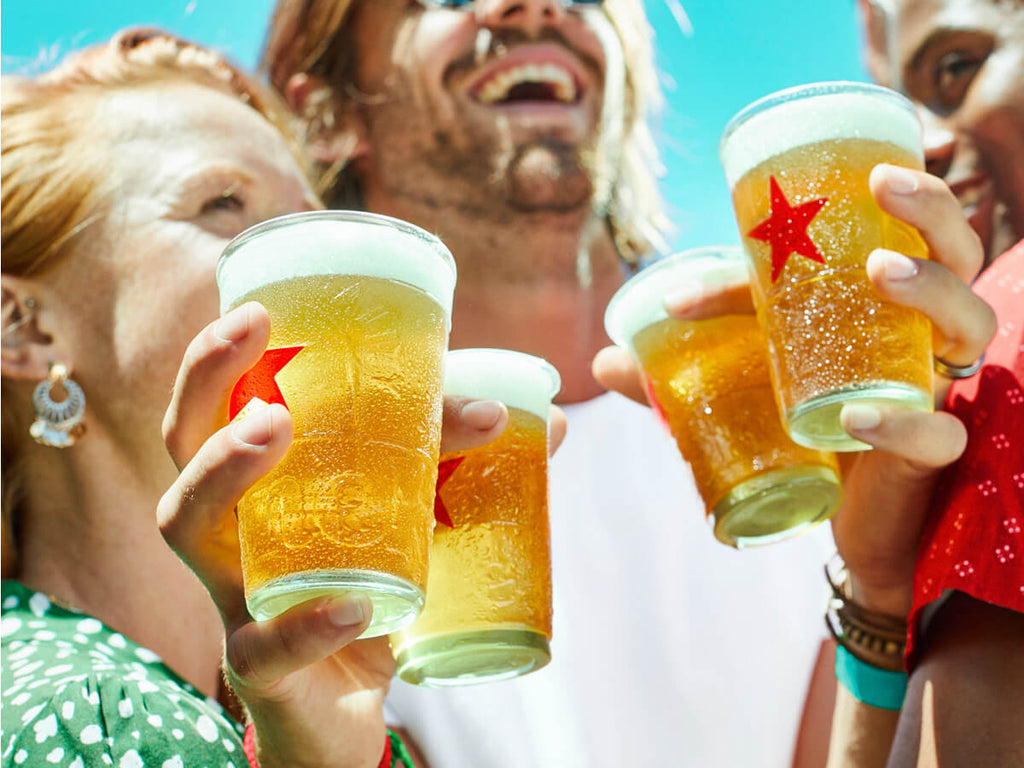 A group of friends enjoy freshly poured glasses of Heineken Silver beer in the sun.