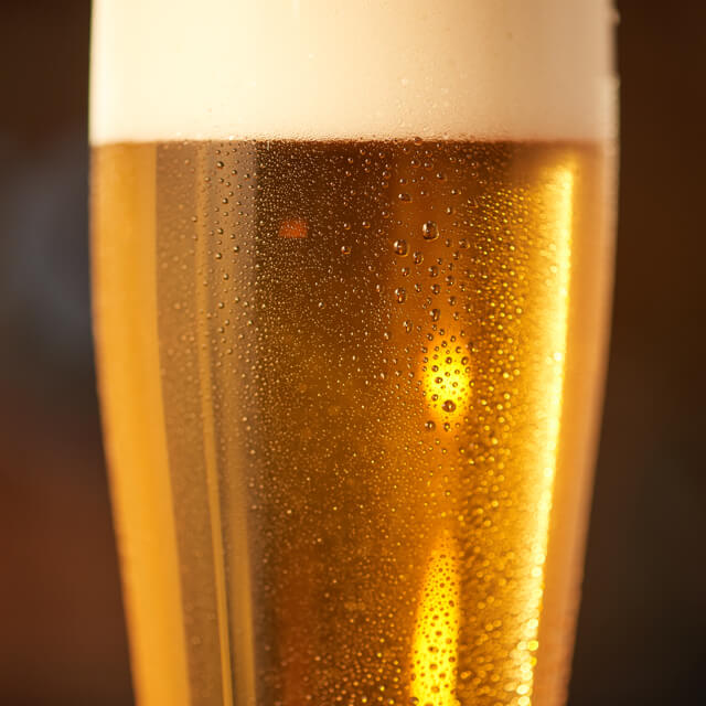 Close up of a beer glass with fresh lager beer and foam